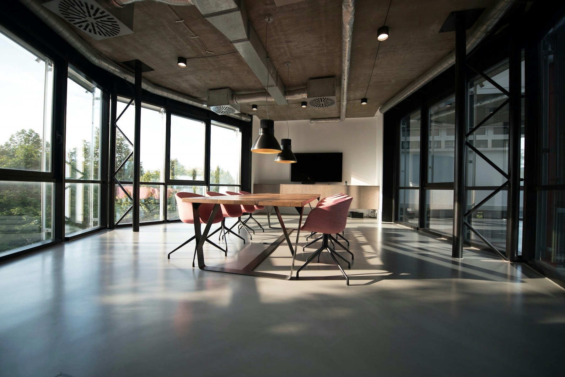 Illustrative photograph of a sunlit meeting room with burgundy chairs; not this suite.